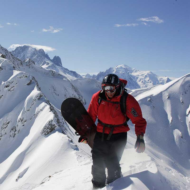 Person carrying a snowboard on a mountain